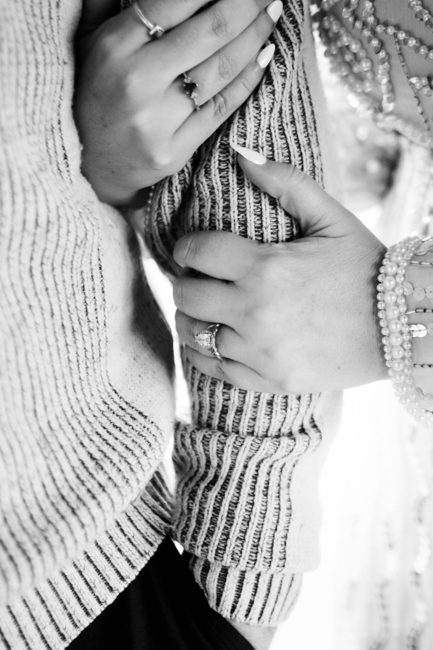 bride holding grooms arm and showing engagement ring