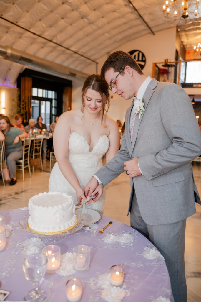 bride and groom cutting small white wedding cake