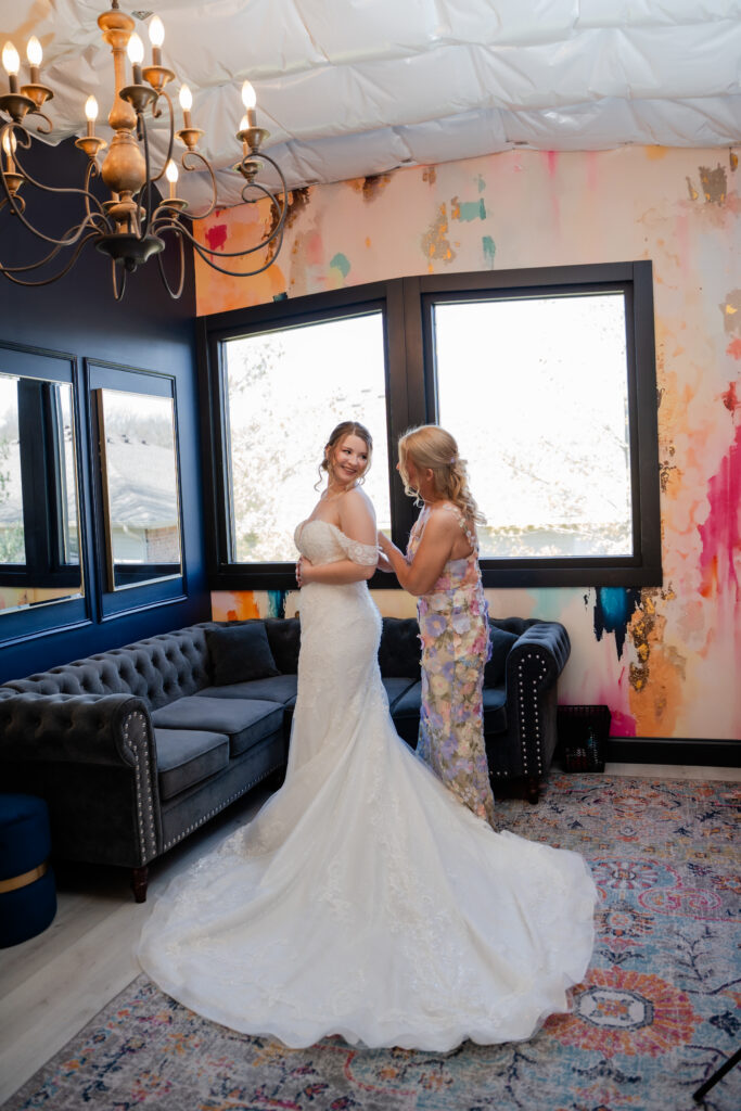 mom zipping up brides dress in echo creeks bridal suite with colorful walls