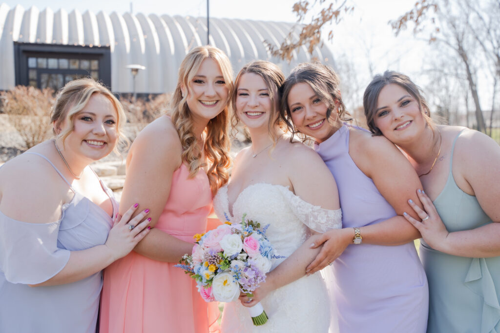 pastel bridesmaids dresses with a bride all smiling at the camera