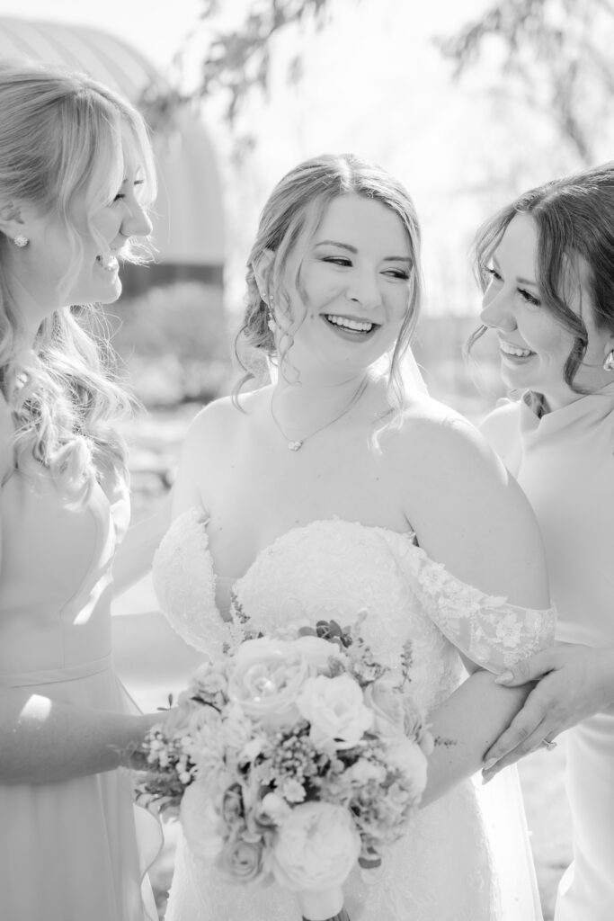 black and white wedding image of bride smiling at her bridesmaids